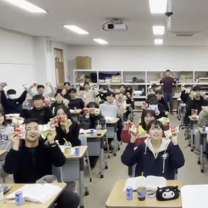 자리에 앉은 학생들이 양손에 간식을 들고 환하게 웃고 있는 모습